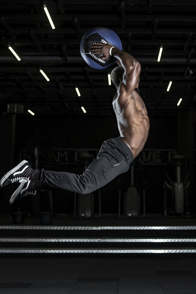 Man Jumping in Mid Air Holding Blue Ball Above His Head