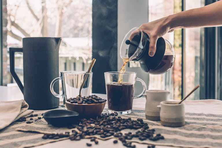 Person Filling Clear Glass Mug With Coffee