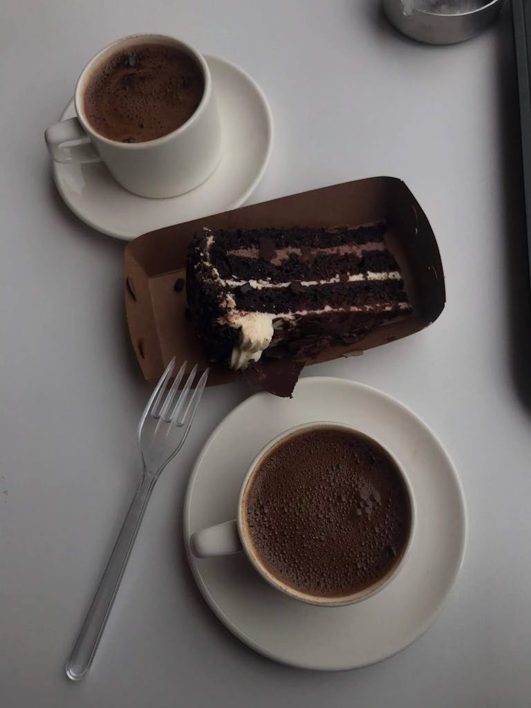 Two cups of coffee and a piece of cake on a table