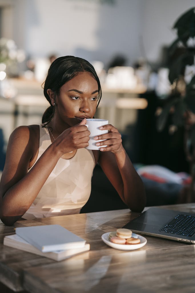 A Woman Drinking Coffee While Sitting at a Table - coffee and Blood Pressure