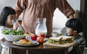 Crop woman standing at table near kids