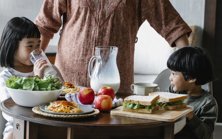 Crop woman standing at table near kids