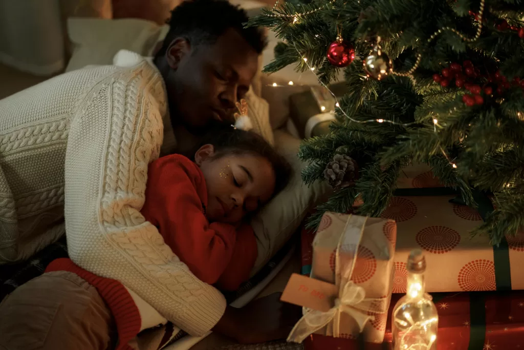 Peaceful moment between a father and daughter sleeping by the Christmas tree. Holiday Season