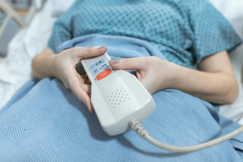 Close-up of a patient's hands holding a remote control in a hospital bed, showing care and medical settings.