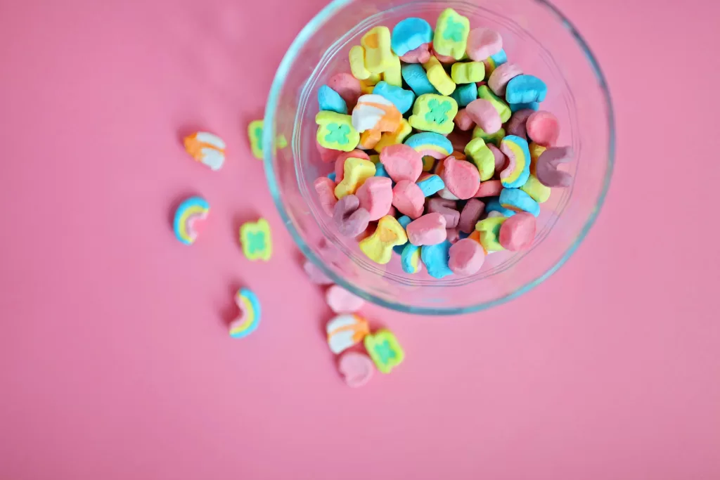 Bright and colorful marshmallow candies in a glass bowl on a pink backdrop, perfect for sweets lovers. - Red Dye No. 3