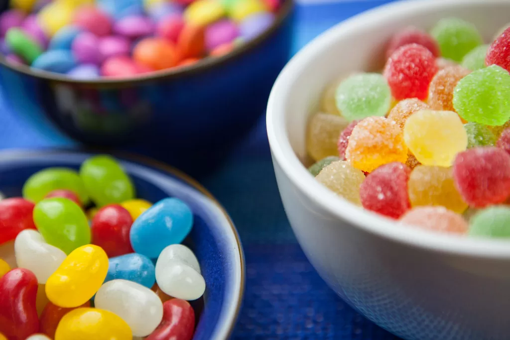 Vibrant assortment of colorful jelly beans and sugar-coated gumdrops in decorative bowls. Perfect for sweet-themed designs.