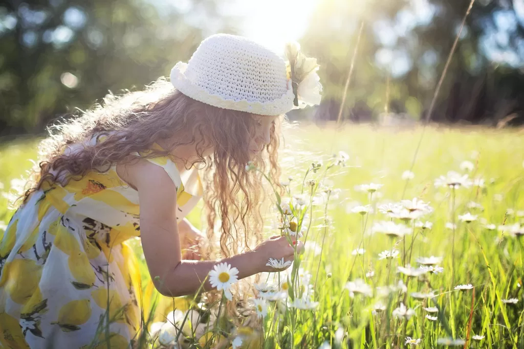 Little girl enjoys picking flowers in a sunlit meadow, embodying pure joy and innocence. Easter