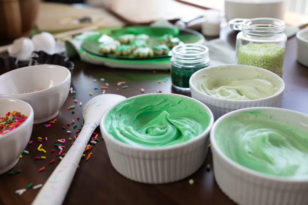 Colorful green frosting and sprinkles in bowls for holiday cookie decoration. Green dyes